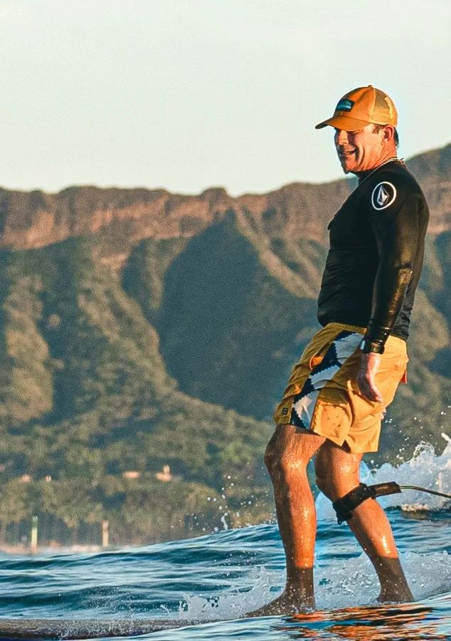 Scott “Uncle Savage” Minkler riding a wave with Diamond Head behind him