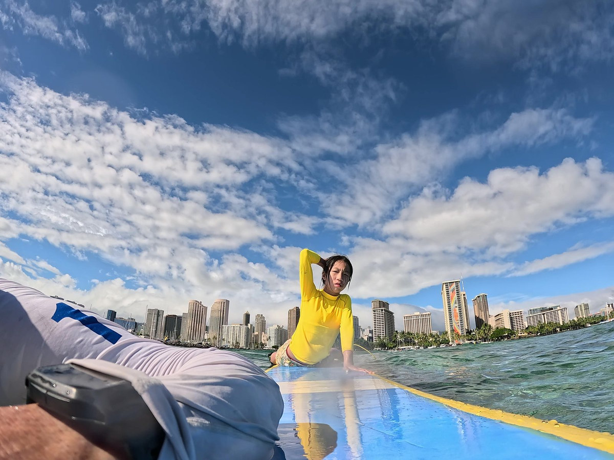 One surfer on a board during close SFC coaching in Waikiki water
