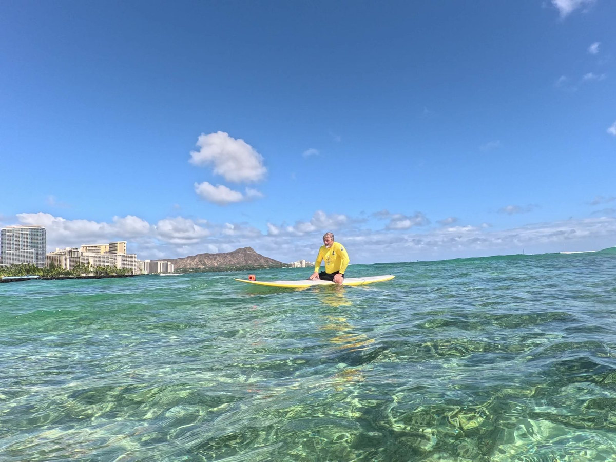 A private SFC surf lesson student riding Waikīkī water with Diamond Head behind them