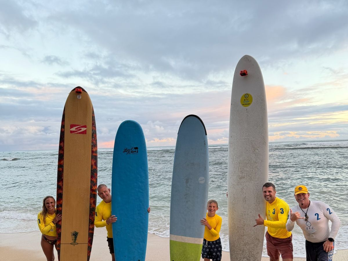 A family crew with boards at sunset after their Waikiki lesson