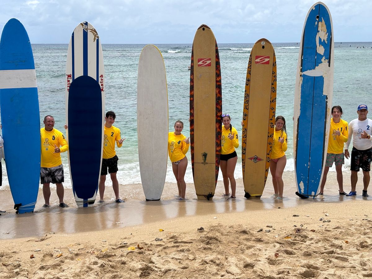The lesson crew with longboards on the beach by the Ala Wai Harbor