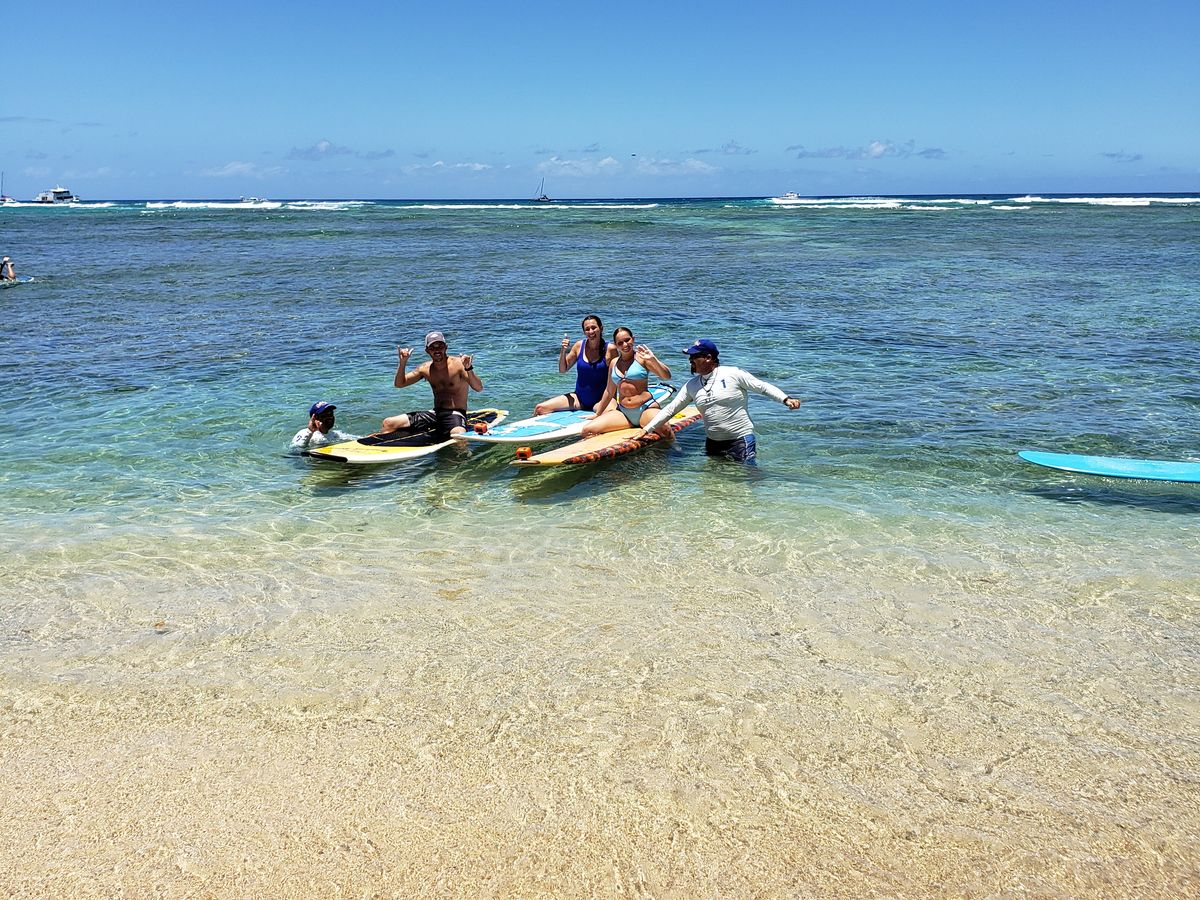 A lesson group walking boards through shallow Waikiki water