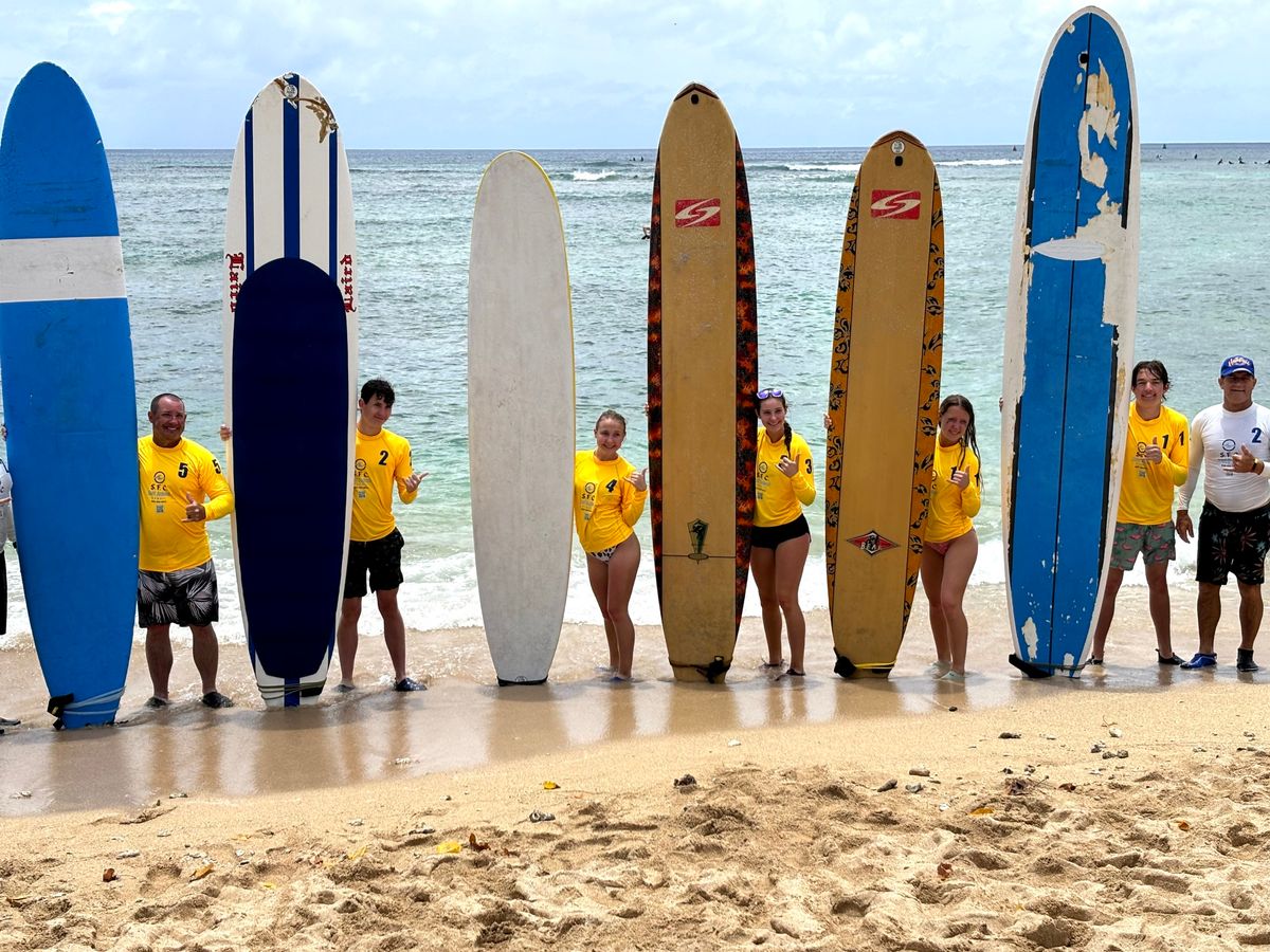Kids and adults holding lesson boards together on the Waikiki beach