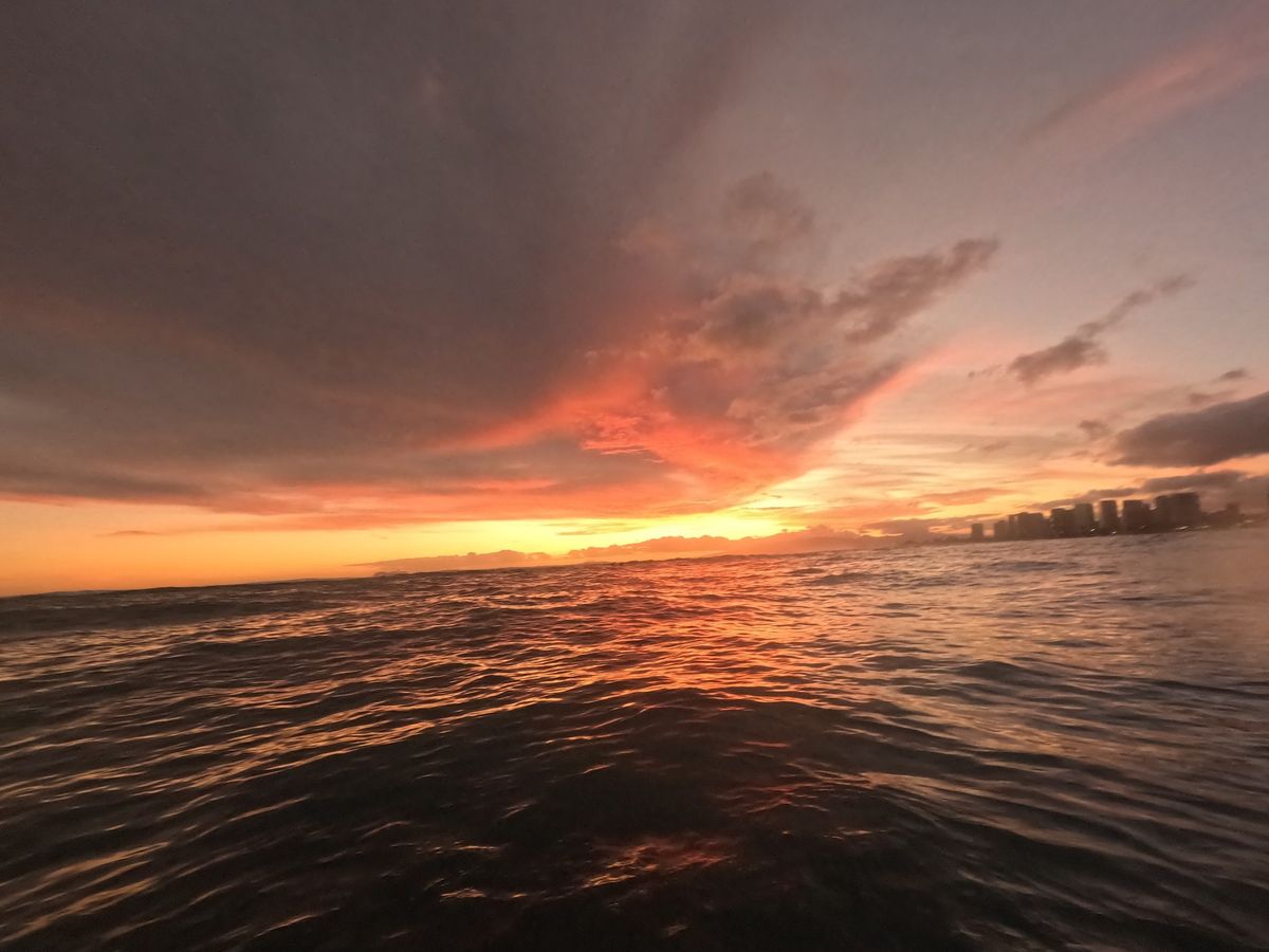 A sunset surf session stretching toward the Oahu horizon