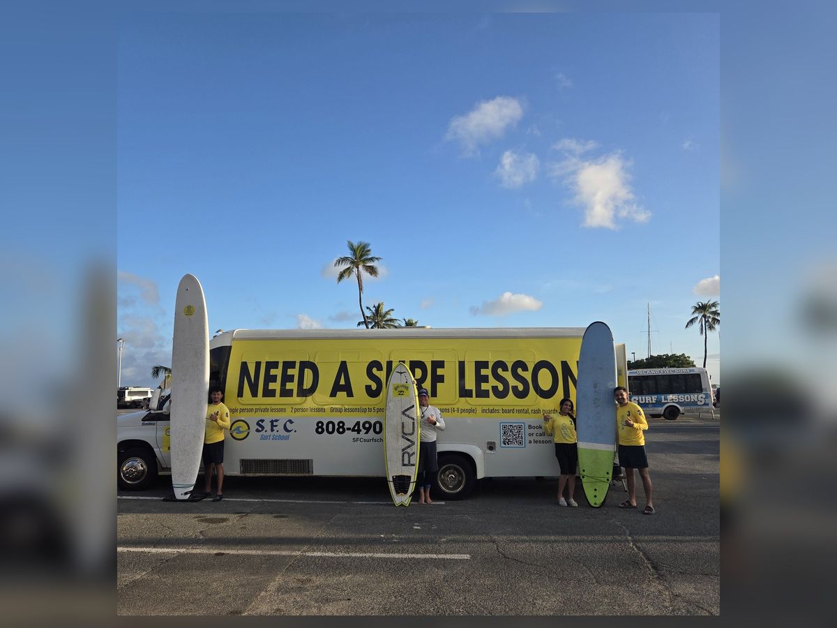 The marked SFC “Need a surf lesson?” bus in Waikīkī with instructors and boards
