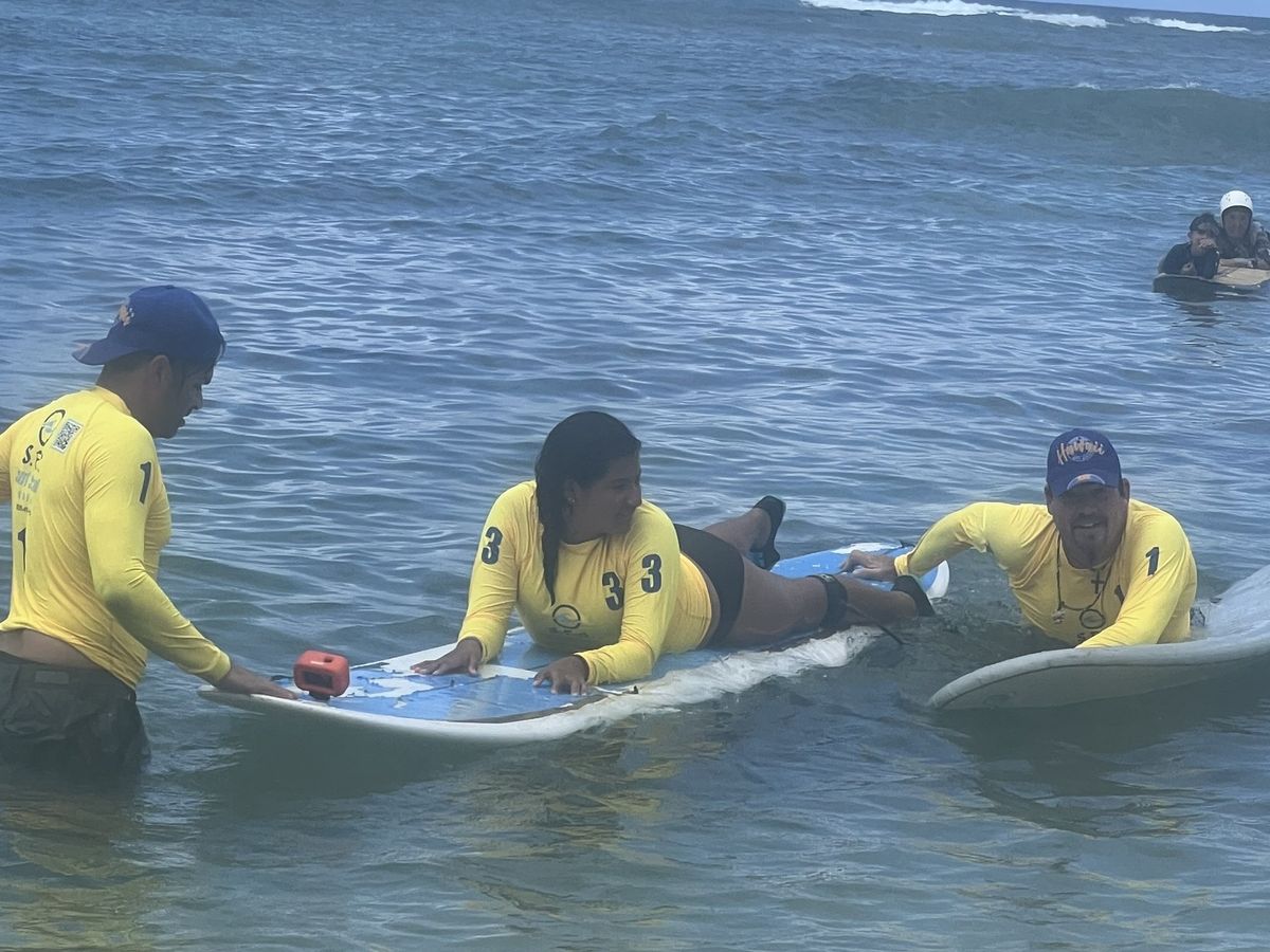 SFC students walking their boards into the Oahu water together