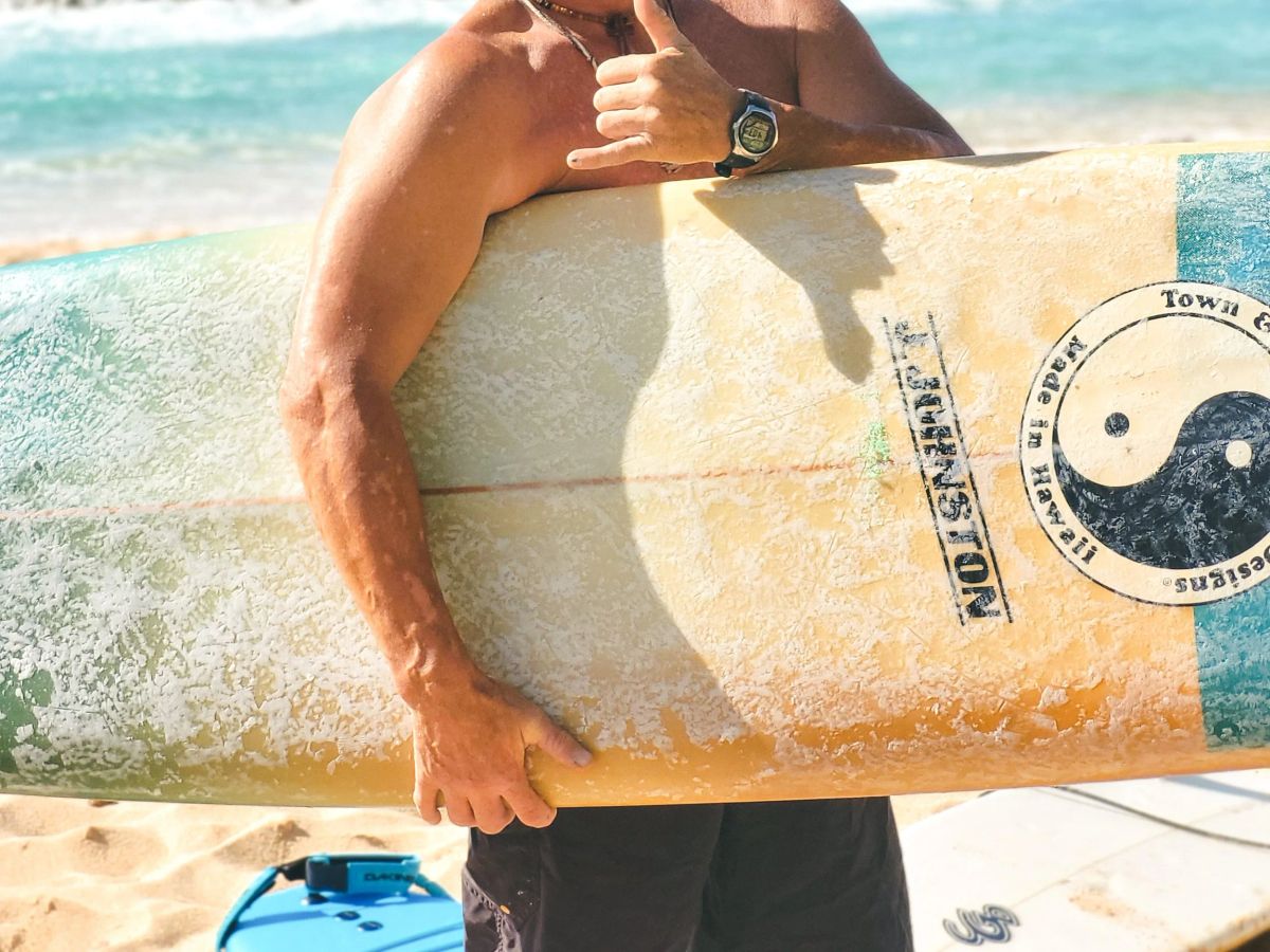 A close view of an SFC surfboard held on the sand