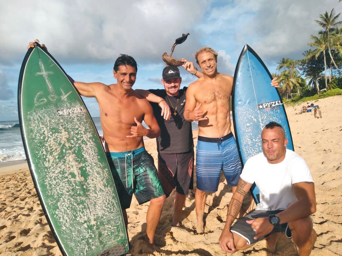 Three surfers standing with their boards on the Waikīkī sand