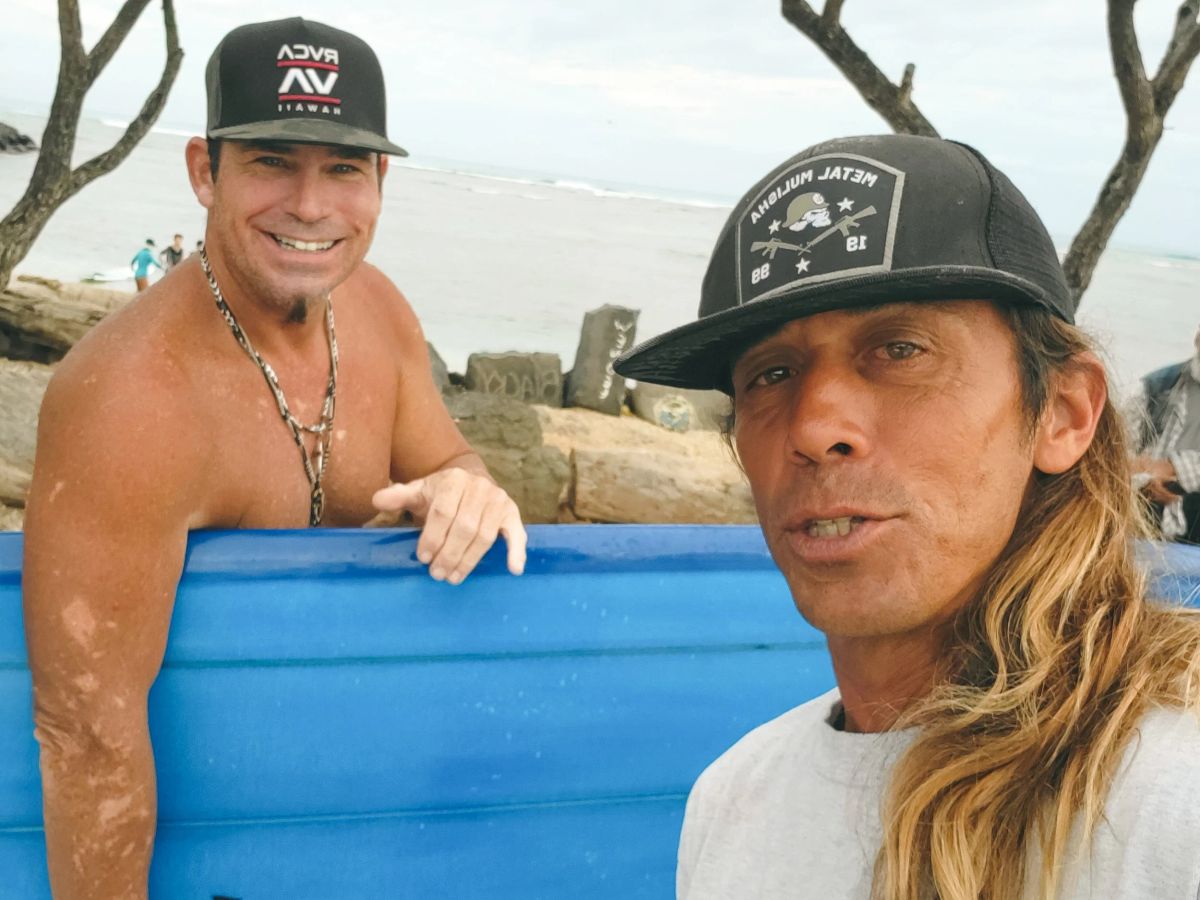 Two surfers smiling together near the Waikīkī shoreline